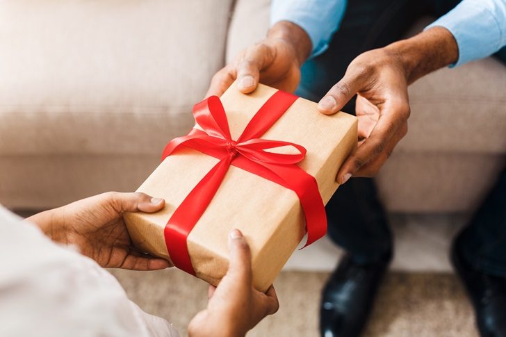 Father Giving Gift to Daughter Close Up one person gives another a gift box with a red bow